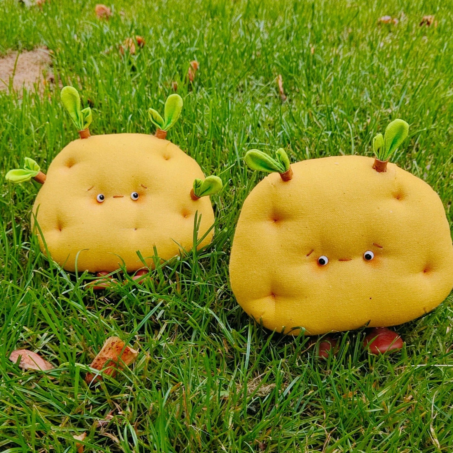 Two yellow plush toys shaped like pears on a grassy background