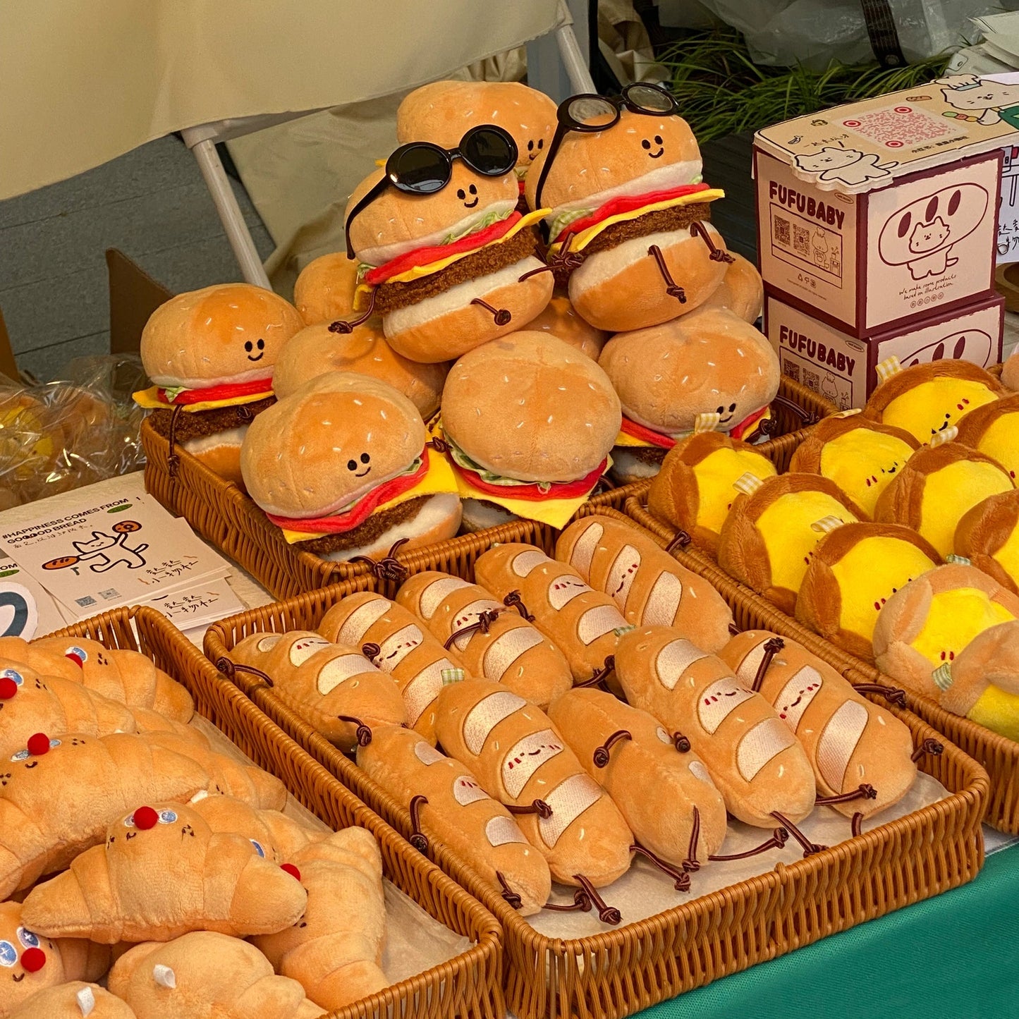 Plush toys resembling hamburgers and buns on display at a market stall.