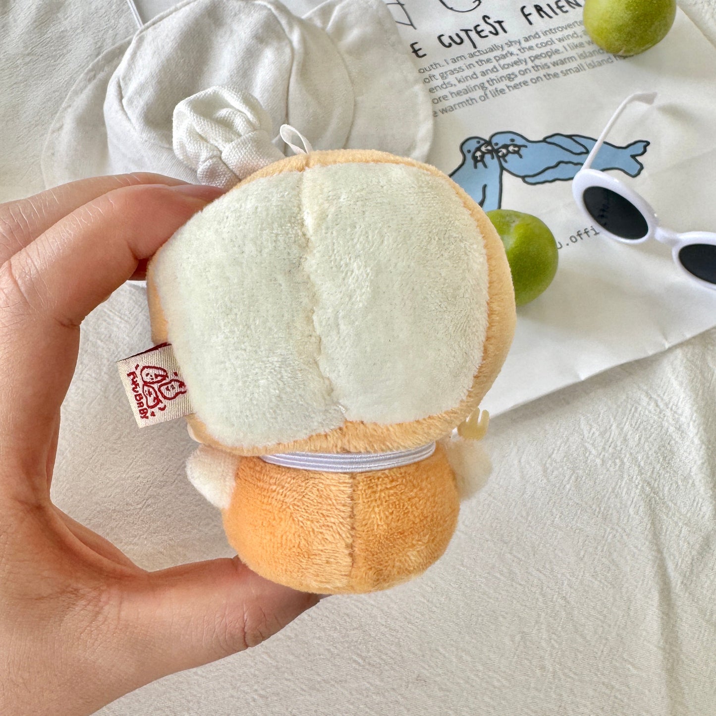Plush toy resembling a moon or cloud held by a hand on a light background