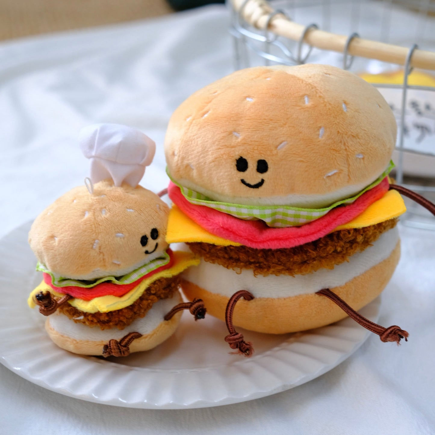 Two plush toy hamburgers on a white plate with a white background