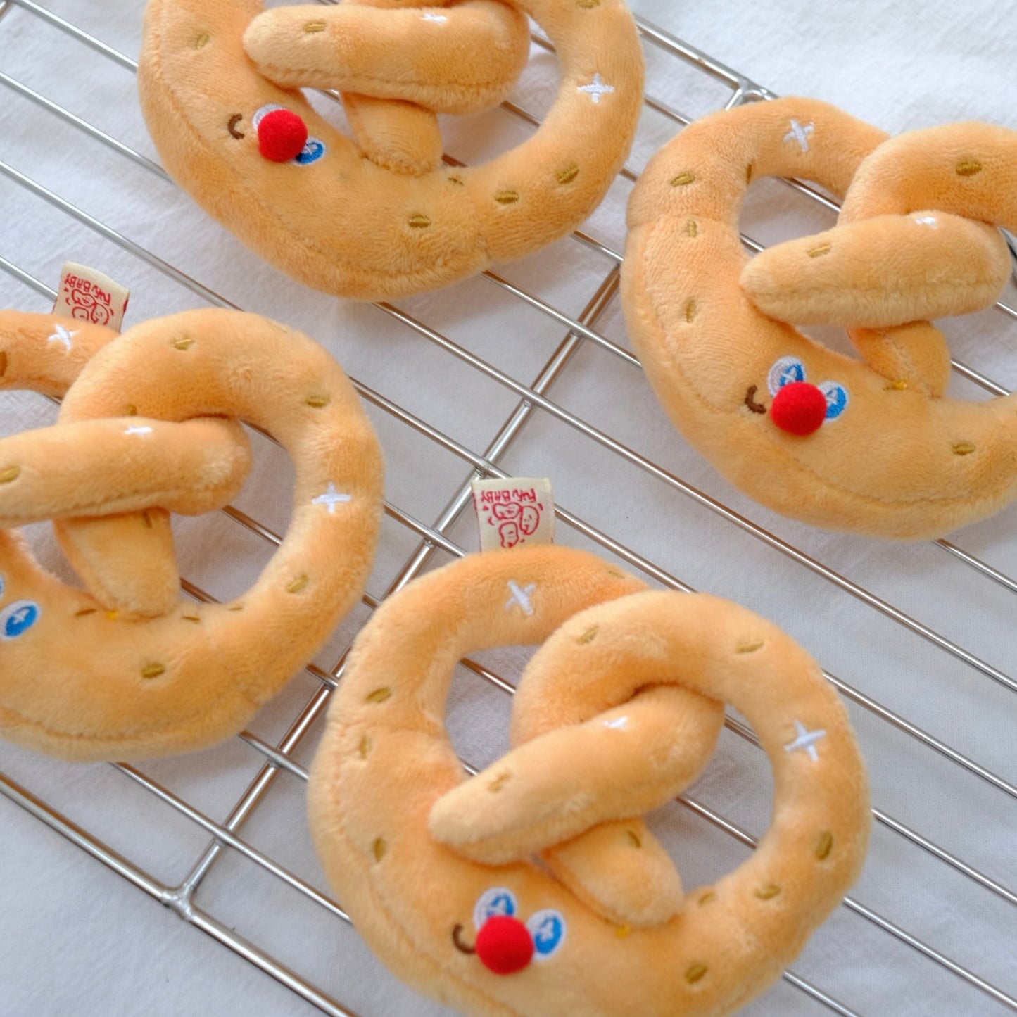 Decorative pretzels with facial expressions on a cooling rack.