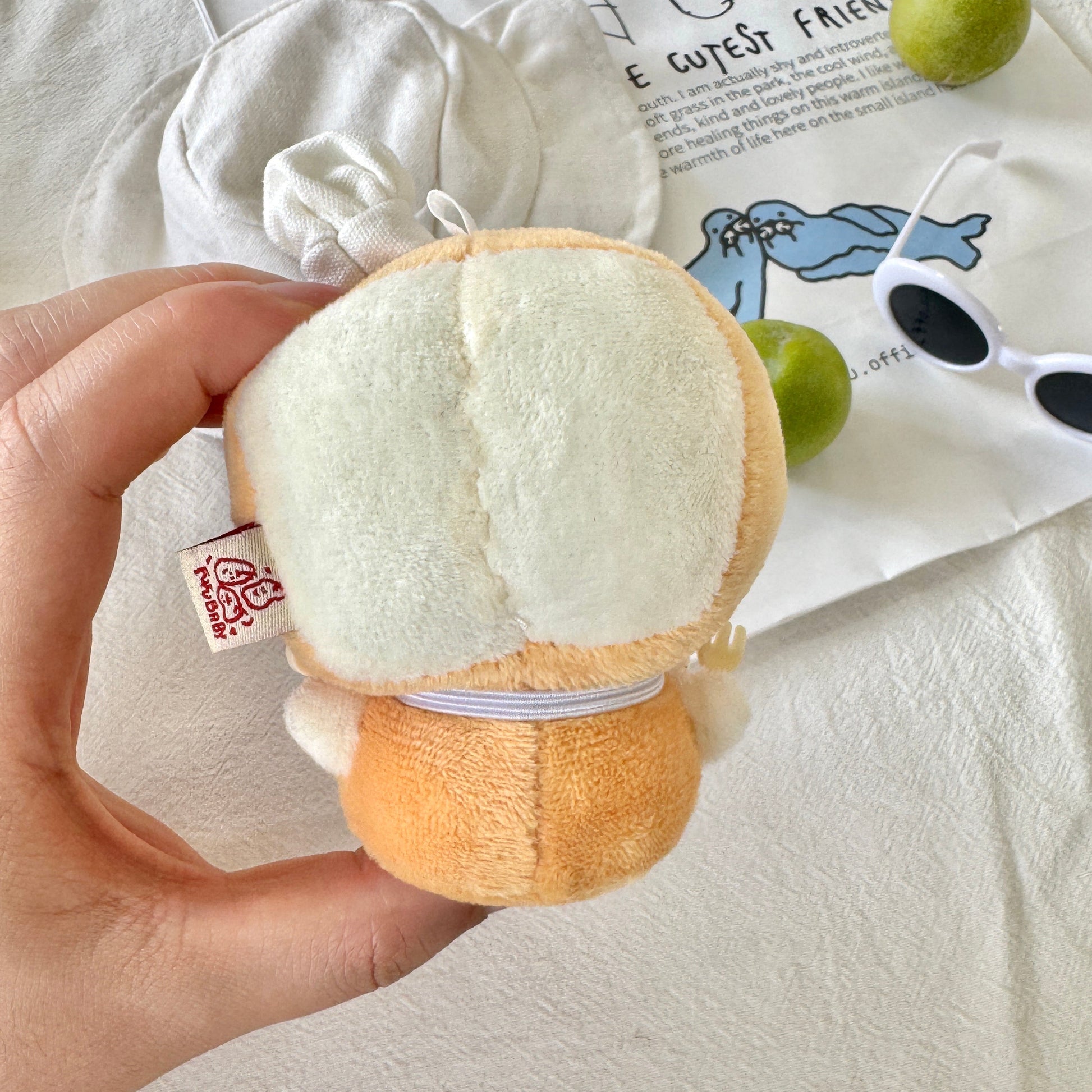 Plush toy resembling a moon or cloud held by a hand on a light background